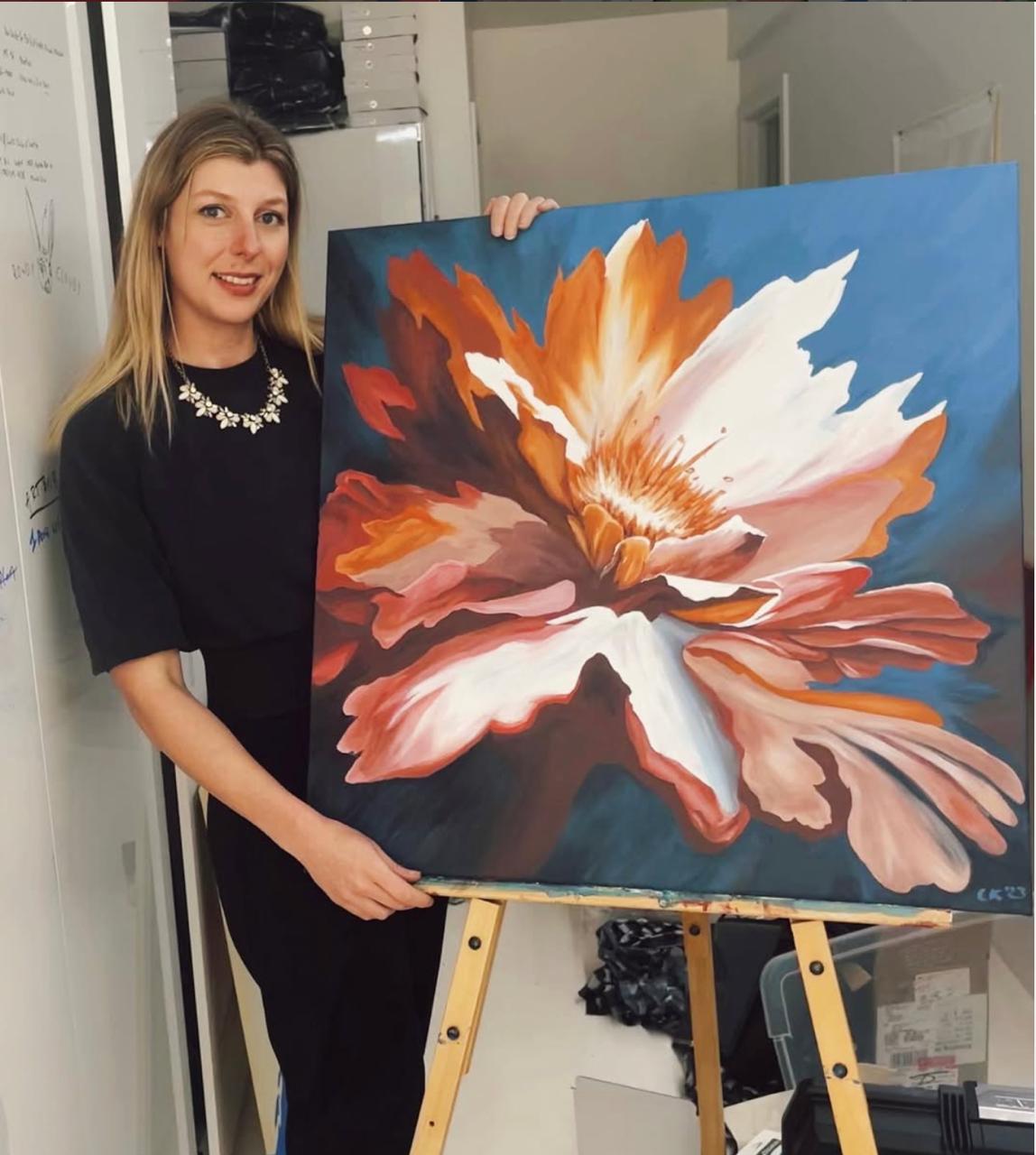 Chelsea Klukas, Seattle-based independent painter, standing with floral artwork